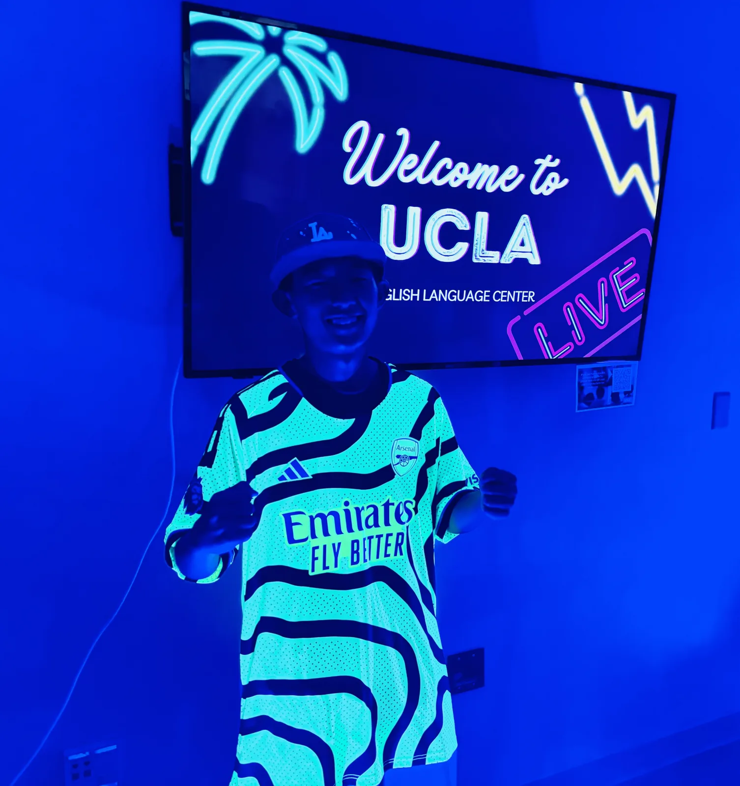 A student in front of a Welcome to UCLA screen at ELC orientation