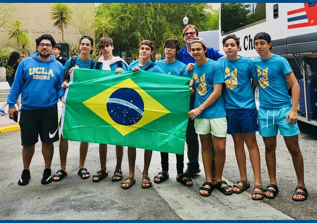 ELC students holding the Brazilian flag beside the excursion bus at UCLA
